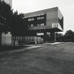 Empty road by buildings against sky in city