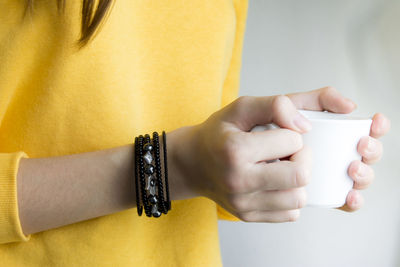 Close-up of woman hand with tattoo against gray background