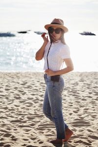 Portrait of woman wearing sunglasses while standing at beach