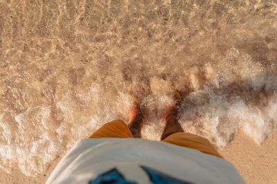 Low section of man standing at beach