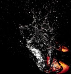 Close-up of firework display over sea against black background