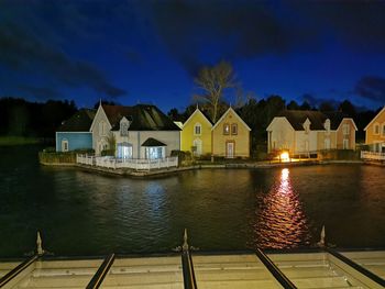 Houses by lake against sky at night