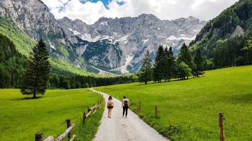 Rear view of two women walking on footpath leading towards mountain 