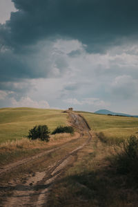 Road amidst field against sky