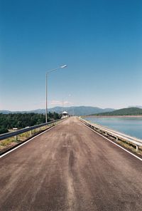 Road by street against clear blue sky