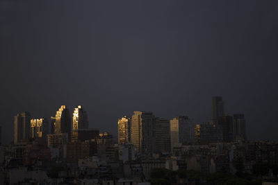 Modern buildings in city against clear sky at night