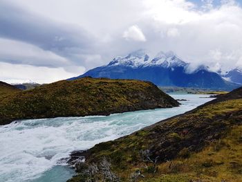 Scenic view of river amidst mountains against cloudy sky