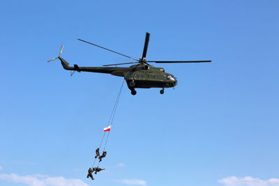 Low angle view of helicopter flying against blue sky