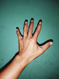 Close-up of hand against blue wall