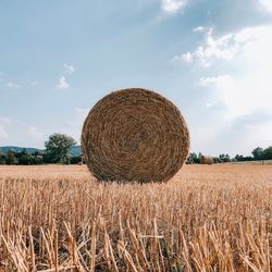 Hay bales on field against sky