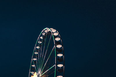 Low angle view of illuminated ferris wheel against blue sky at nicht 