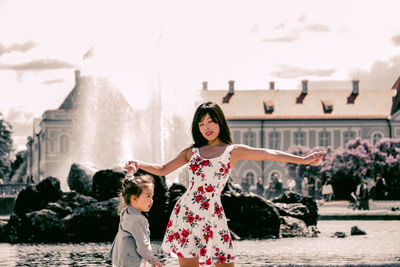 Woman dancing with daughter against fountain