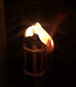 Close-up of lit candle in dark room