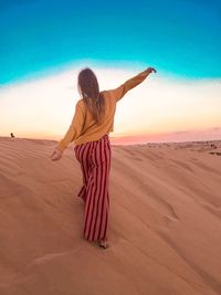 Rear view of woman on sand in desert against sky