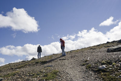 Low angle view of friends standing on hill against sky