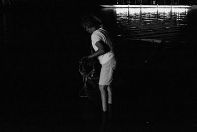 Side view of boy standing in dark room