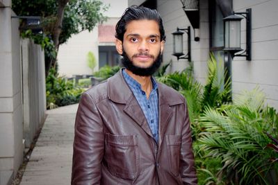 Portrait of young man standing against building