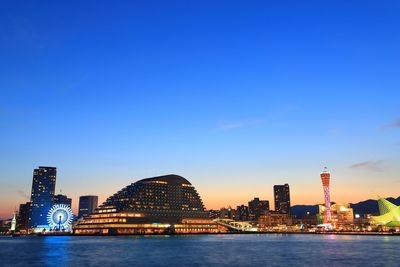 Illuminated buildings in city against blue sky