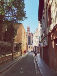 Road amidst buildings in city against clear sky