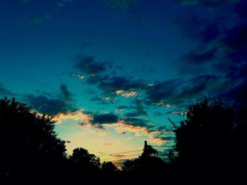 Silhouette of trees against cloudy sky