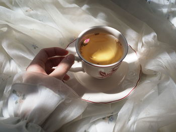 Midsection of person holding ice cream on bed