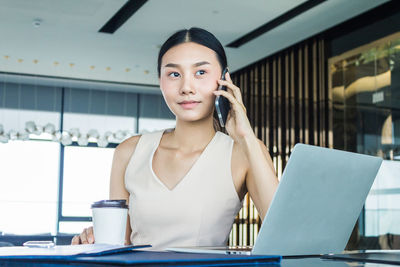 Portrait of young woman using phone on table