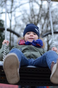 Cute girl sitting on swing in winter