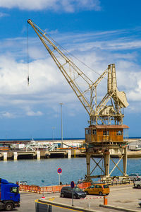 Crane at harbor against sky