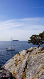 Sailboat on rock by sea against sky