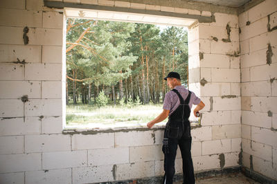 Side view of young woman standing against wall