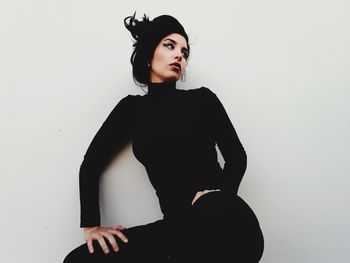 Portrait of young woman standing against white background