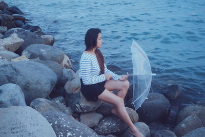 Woman standing on rocks by sea