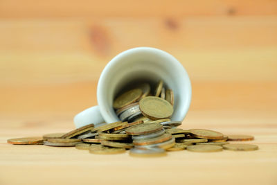 Close-up of coins spilling on wooden table