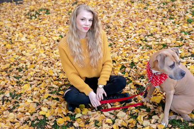 Portrait of teenage boy with dog in autumn leaves