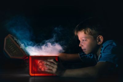 Side view of curious boy opening smoky box in darkroom