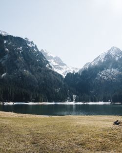 Scenic view of lake by snowcapped mountains against sky