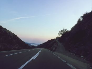 Empty road by mountains against sky