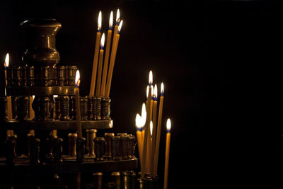 Close-up of lit candles in stand against black background