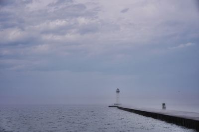 Lighthouse by sea against sky