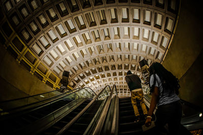 Rear view of people walking on escalator in city