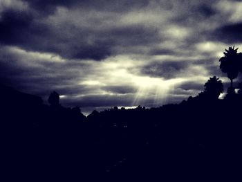 Silhouette of trees against cloudy sky