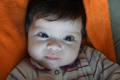 Portrait of cute baby girl lying on bed