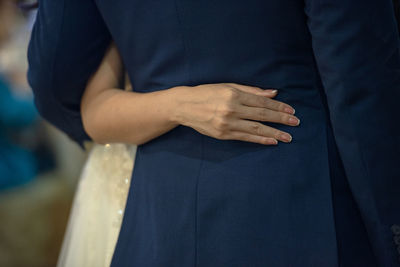 Midsection of bride and bridegroom embracing