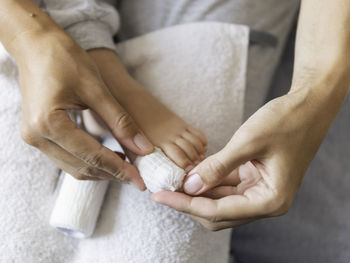 Cropped hand of mother wrapping bandage on kids fit