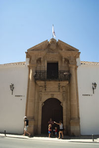 People in front of historical building against clear sky