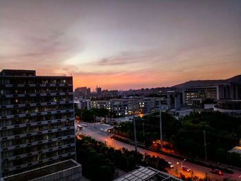 High angle view of illuminated cityscape against sky at sunset