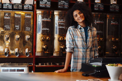 Smiling owner standing at cash register in coffee roastery