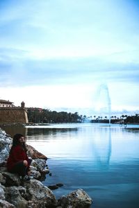 Rear view of woman sitting against sky