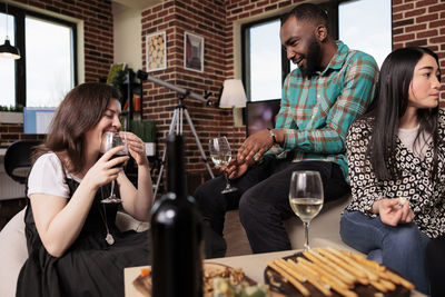 Smiling friends using smart phone while sitting at restaurant