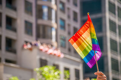 Cropped hand holding rainbow flag in city